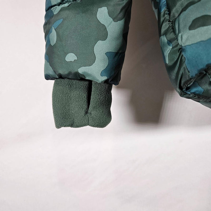Load image into Gallery viewer, Detailed view of the coat sleeve, showing the green camo pattern, thumb hole, and ribbed cuff for snug fit to protect against the cold.
