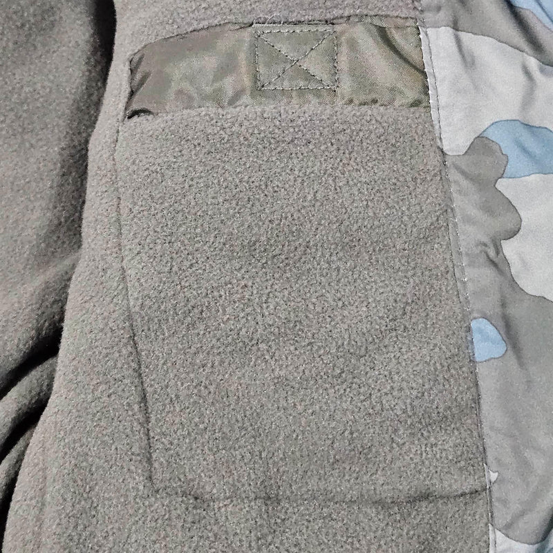 Load image into Gallery viewer, Close-up of the pocket on the green camo puffer coat, illustrating the secure zip and reinforced stitching for durability.
