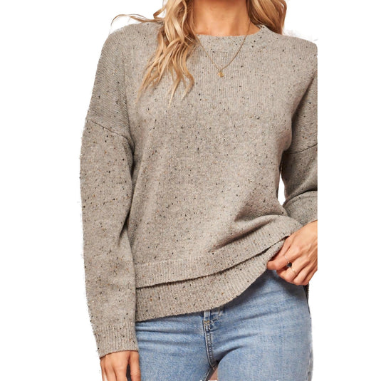 Close-up of a cozy oatmeal flecked knit sweater with a crew neckline and long sleeves, highlighting the texture.