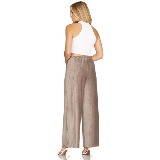 Rear view of a model in white sleeveless crop top and mocha velvet pants with a comfortable elastic waistband, showcasing a relaxed fit.