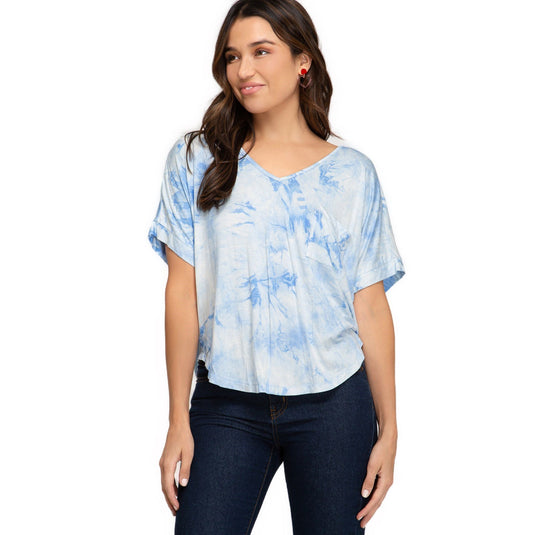 Chic woman in a blue tie-dye V-neck top with folded drop shoulders, paired with dark jeans, perfect for a casual yet trendy look.