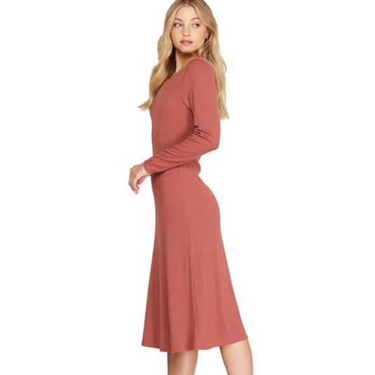 Side view of a dusty coral colored long sleeve midi dress, accentuating the garment's smooth lines and understated elegance with its soft knit fabric and slight hem flare.