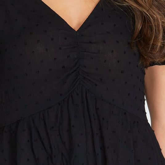 Close-up of the black Short Sleeve V-neck Ruched Blouse focusing on the V-neckline and Swiss dot details, offering a textured look to the elegant design.