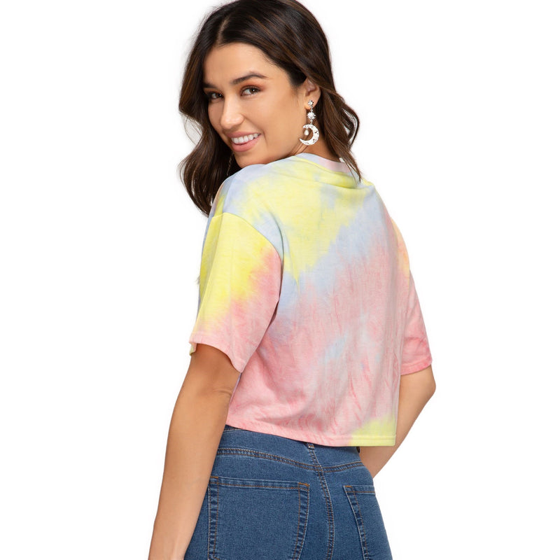 Load image into Gallery viewer, Rear view of a woman wearing a yellow/pink tie-dye Short Sleeve V Neck Terry Crop Top, showcasing the loose fit and cropped length that pairs well with high-waisted denim.
