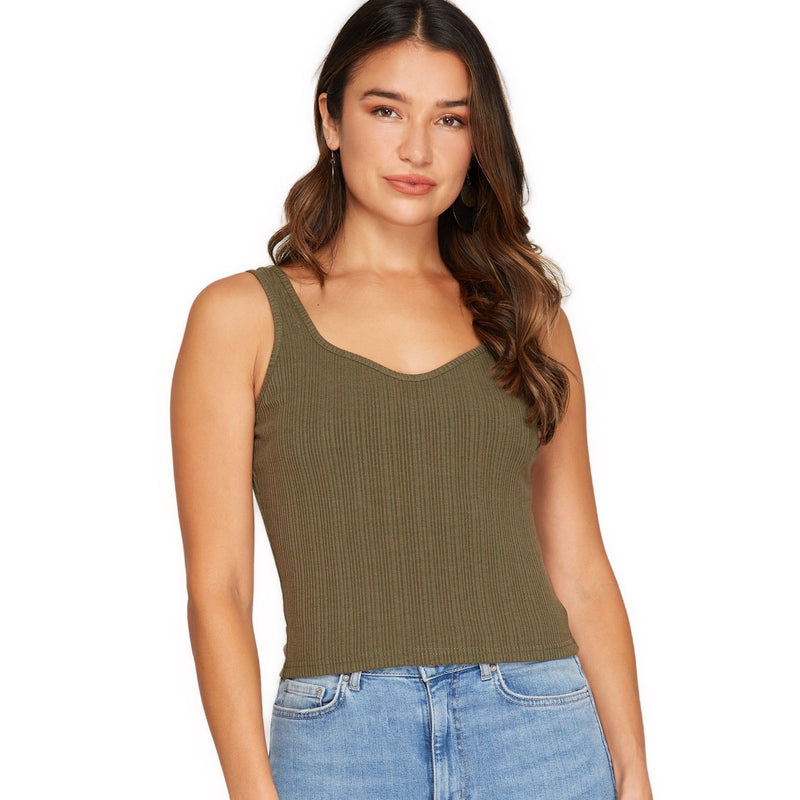 Load image into Gallery viewer, A confident woman showcases a sleeveless, ribbed crop top in a deep olive green shade, paired with light-wash denim jeans for a smart-casual look.
