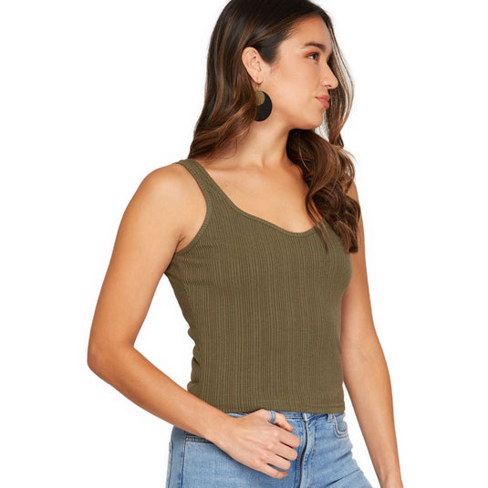 A side-profile view of a woman in an olive green ribbed crop top, showing off the fit and cut that hugs the waistline for a flattering silhouette.