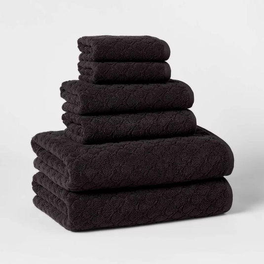 A neatly stacked set of six luxurious black bath towels made from 100% cotton, showcasing the ultra-soft texture that enhances your bathing experience.