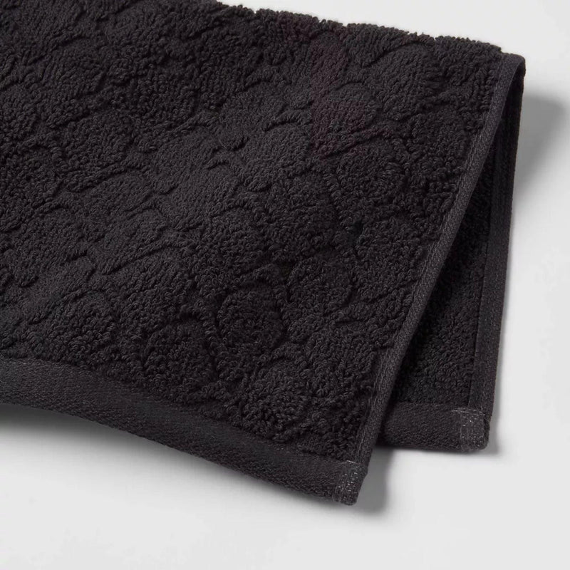 Load image into Gallery viewer, Close-up of the richly textured surface of a black cotton bath towel, highlighting the intricate pattern that adds a touch of elegance to the bathroom.

